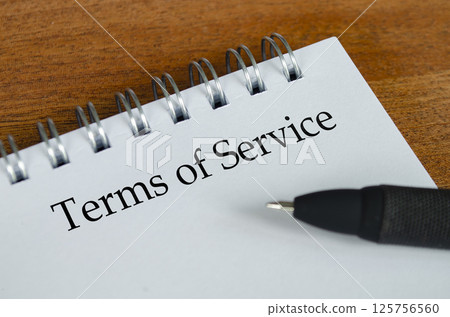 Terms of Service text on white notepad with wooden table background. Terms of Service concept. Terms of Service text on white notepad with wooden table background. Terms of Service concept. 125756560