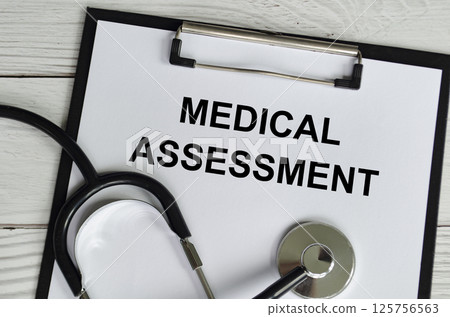 Top view of Medical Assessment Text on white paper clipboard with stethoscope on wooden table background. Health and medical concept. 125756563