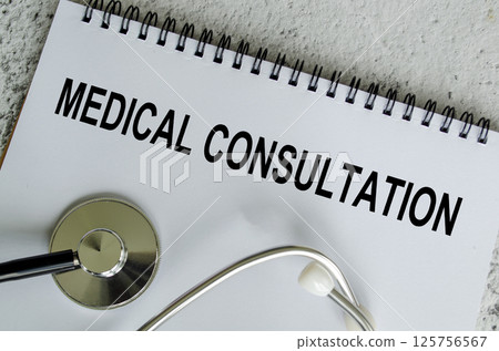 Top view of Medical Consultation Text on white paper notepad with stethoscope on wooden table background. Health and medical concept. Top view of Medical Consultation Text on white paper notepad with stethoscope on wooden table background. Health and medical concept. 125756567