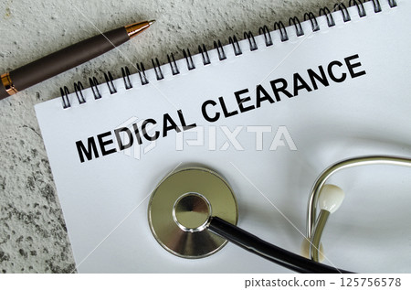 Top view of Medical Clearance Text on white paper notepad with stethoscope on wooden table background. Health and medical concept. 125756578