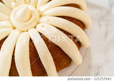 Icing the pumpkin bundt cake with cream cheese frosting and decorating it with chocolate leaves. 125757043