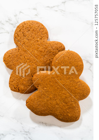 A stack of Orange Zest Gingerbread Cookies in gingerbread girl shapes on a white surface, showcasing their festive design and uniform texture. 125757058