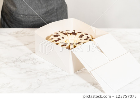 Packaging the freshly baked pumpkin bundt cake into a white paper box for gifting. Packaging the freshly baked pumpkin bundt cake into a white paper box for gifting. 125757073