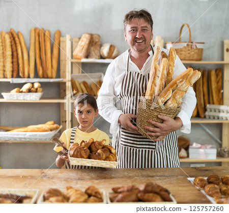 Baker dad and daughter are standing near product range in bakery kitchen. 125757260
