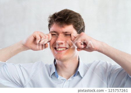 Portrait of young guy with itchy eyes in studio 125757261
