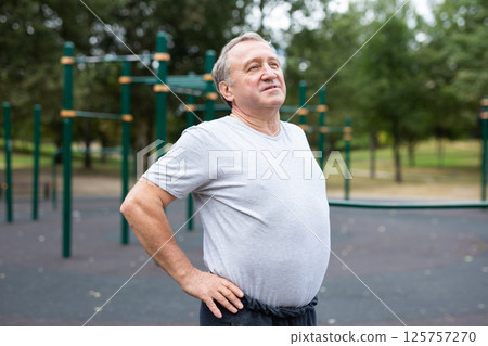 Elderly man doing gymnastics on an outdoor sports ground Elderly man doing gymnastics on an outdoor sports ground 125757270