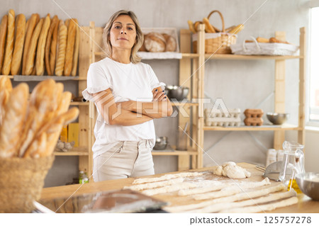Elderly woman baker posing in bakery 125757278