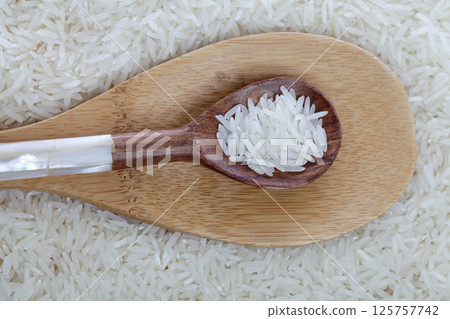 Dry raw long grain rice on wooden spoon, top view Dry raw long grain rice on wooden spoon, top view 125757742