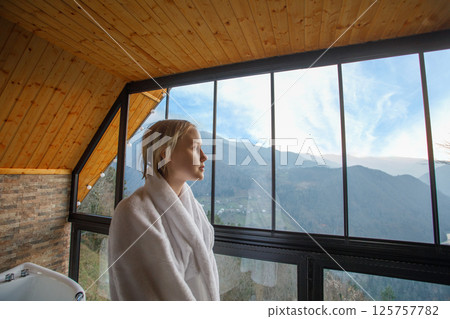 Blonde woman in white bathrobe looking on the mountains in Variaki, Georgia 125757782