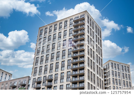 Modern apartment building with balconies and glass windows under blue sky Modern apartment building with balconies and glass windows under blue sky 125757954