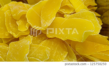 Dried mango strips lie on the counter in a supermarket. Prepared for sale. Dried mango strips lie on the counter in a supermarket. Prepared for sale. 125758250