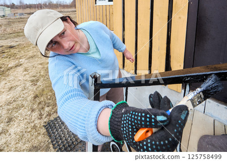 Using sturdy brush to spread paint on metal railing, enthusiastic house painter enjoys process of transforming entrance with each careful stroke. Using sturdy brush to spread paint on metal railing, enthusiastic house painter enjoys process of transforming entrance with each careful stroke. 125758499