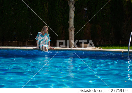 Woman Relaxing by a Serene Pool on a Sunny Day Outdoors 125759394
