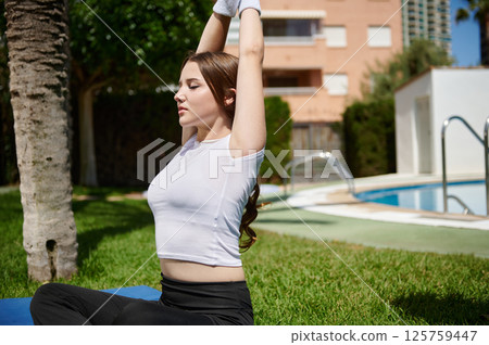 Young Woman Practicing Yoga Outdoors Near Swimming Pool in Sunny Weather Young Woman Practicing Yoga Outdoors Near Swimming Pool in Sunny Weather 125759447
