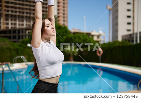 Young Woman Stretching by a Poolside on a Sunny Day 125759449