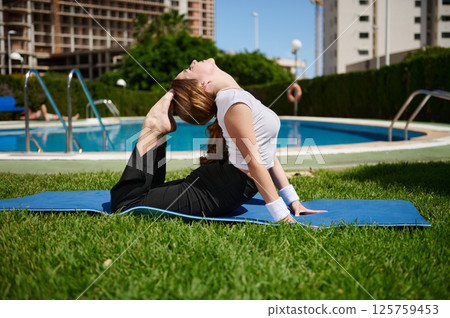 Woman Performing Yoga Poses Outdoors by a Pool on a Sunny Day Woman Performing Yoga Poses Outdoors by a Pool on a Sunny Day 125759453