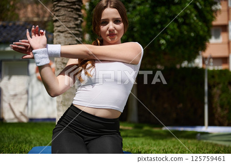 Woman in Activewear Stretching Outdoors in a Sunny Park Setting 125759461