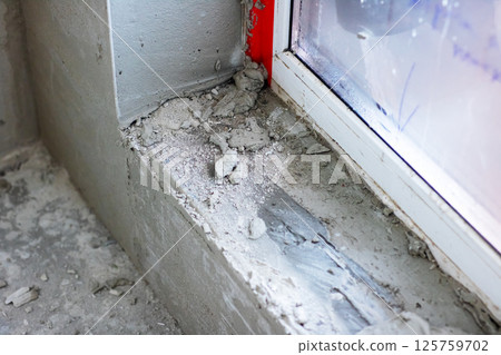 A window sill with a significant buildup of concrete over time 125759702