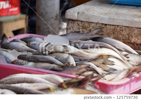 Fresh fish displayed on ice in a pink tray at a market, ready for sale. 125759730