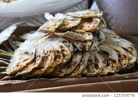 Dried fish neatly stacked in a cardboard box, showcasing preserved seafood ready for sale or storage. Dried fish neatly stacked in a cardboard box, showcasing preserved seafood ready for sale or storage. 125759776