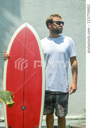 A surfer riding the waves with a bright red surfboard on a beautiful summer day at the beach A surfer riding the waves with a bright red surfboard on a beautiful summer day at the beach 125759802