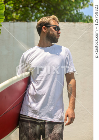 A Surfer Relaxing with a Paddleboard in a Beautiful Tropical Setting by the Beach A Surfer Relaxing with a Paddleboard in a Beautiful Tropical Setting by the Beach 125759823