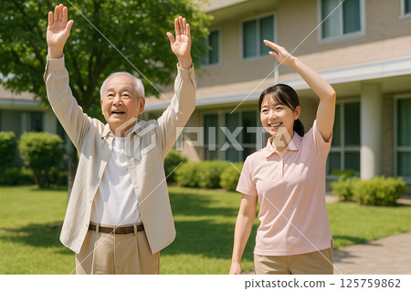 An elderly man and his caregiver doing exercises together in the garden of a care facility An elderly man and his caregiver doing exercises together in the garden of a care facility 125759862