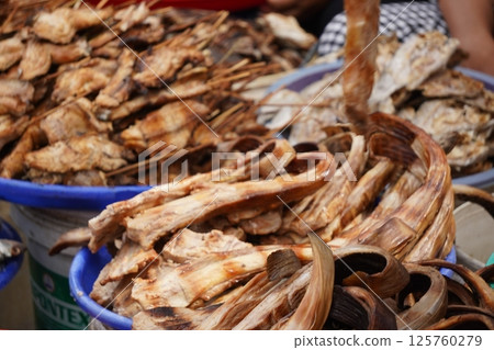 Smoked fish piled in a basket, ready for sale at a market, showcasing a popular street food or local delicacy. Smoked fish piled in a basket, ready for sale at a market, showcasing a popular street food or local delicacy. 125760279