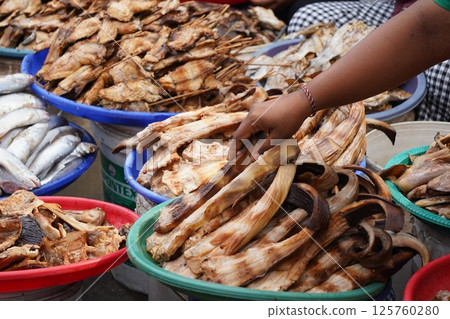 Smoked fish piled in a basket, ready for sale at a market, showcasing a popular street food or local delicacy. Smoked fish piled in a basket, ready for sale at a market, showcasing a popular street food or local delicacy. 125760280