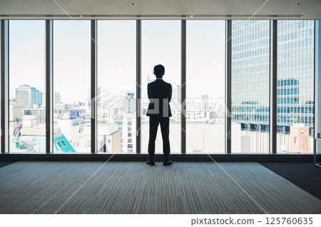 The back of a businessman looking out of a building 125760635