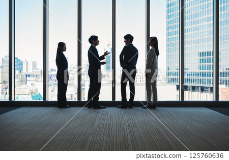 Silhouettes of business people discussing by the window of a building 125760636