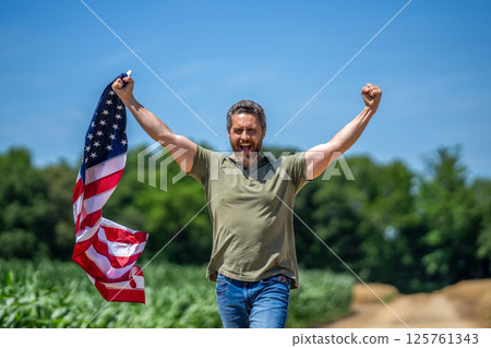 Patriotic man with American flag in field. Independence day of America. 4th of July. Labor day. American flag and man farmer, harvest. Flag of USA. Independence day. Happy man in field Patriotic man with American flag in field. Independence day of America. 4th of July. Labor day. American flag and man farmer, harvest. Flag of USA. Independence day. Happy man in field 125761343