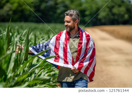Flag of USA. Independence day. Man in field. Patriotic man with American flag in field. Independence day of America. 4th of July. Labor day. American flag and man farmer, harvest. Veterans day Flag of USA. Independence day. Man in field. Patriotic man with American flag in field. Independence day of America. 4th of July. Labor day. American flag and man farmer, harvest. Veterans day 125761344