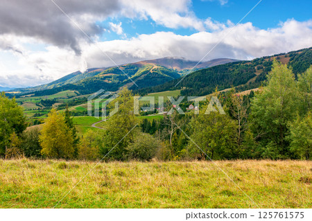 mountain landscape in early autumn for travel. alpine scenery with forest in colorful foliage. beautiful countryside valley with rolling hills. view of carpathian range under sky with clouds mountain landscape in early autumn for travel. alpine scenery with forest in colorful foliage. beautiful countryside valley with rolling hills. view of carpathian range under sky with clouds 125761575