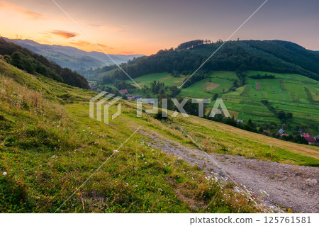 rural landscape in summer. fresh morning. village in the valley at dawn. forest and green meadow on the hill under red sky. scenic view of a countryside in mountains of ukraine rural landscape in summer. fresh morning. village in the valley at dawn. forest and green meadow on the hill under red sky. scenic view of a countryside in mountains of ukraine 125761581