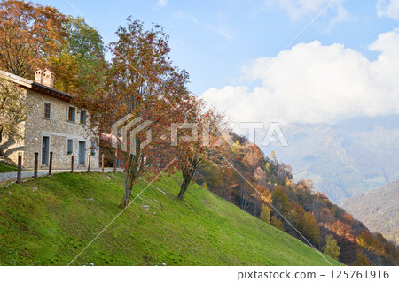 View on house on the mountain side, picturesque Alps autumn landscape, mountain hills in Lombardy, Italy. Tourist adventure 125761916