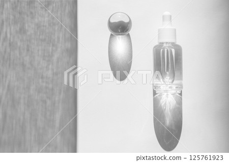 Transparent liquid product packaging in glass bottle. Hyaluronic acid oil mockup. Anti aging serum with collagen and peptides on white surface with sunlight and shadow. Flat lay, copy space 125761923