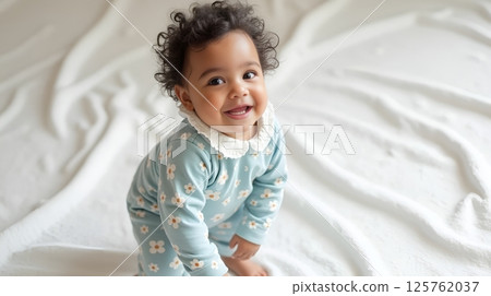 Smiling curly-haired one-year-old baby looking at camera Smiling curly-haired one-year-old baby looking at camera 125762037