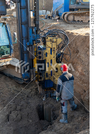 A worker controls the extraction of Larssen sheet piling from the ground 125762275