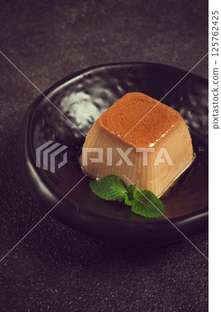cream caramel pudding, with caramel sauce, dessert,breakfast, on a black plate, mint, no people, 125762425