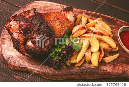 Pork knuckle, in soy-honey sauce, with fried potatoes, on a wooden chopping board, homemade, no people, 125762426