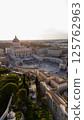 Aerial view of St. Peters Basilica and St. Peters Square in Vatican City at sunset, with surrounding architecture and gardens visible in warm evening light. 125762963