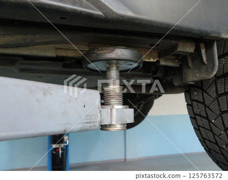 Hydraulic car lift elevating vehicle during professional automotive maintenance and repair service 125763572
