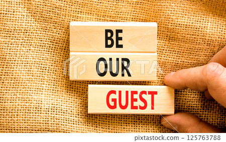 Be our guest symbol. Concept words Be our guest on beautiful wooden block. Businessman's hand. Beautiful canvas background. Business and be our guest concept. Copy space. 125763788