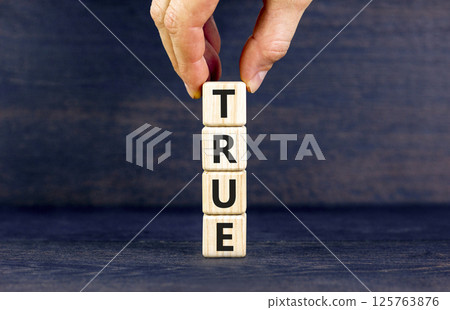 True symbol. Concept word True on beautiful wooden blocks. Businessman hand. Beautiful black table black background. Business, lifestyle, support and true concept. Copy space. 125763876