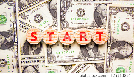 Start symbol. Concept word Start on beautiful wooden circles. Beautiful dollar bills. Beautiful background from dollar bills. Business lifestyle start concept. Copy space. Start symbol. Concept word Start on beautiful wooden circles. Beautiful dollar bills. Beautiful background from dollar bills. Business lifestyle start concept. Copy space. 125763895