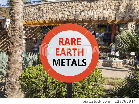Rare earth metals symbol. Concept words Rare earth metals on beautiful big white road sign. Beautiful palm tree hotel market background. Business and rare earth metals concept. Copy space. 125763914