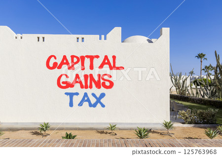 Capital gains tax symbol. Concept words Capital gains tax on beautiful white wall. Beautiful white wall blue sky background. Business and capital gains tax concept. Copy space. 125763968