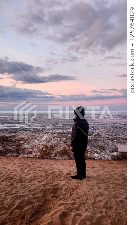 Spring landscape. Panoramic view of beautiful dawn on bay. Cumulus clouds over water in bright light. Ice, snow and rocks on coastline. Rising rays of sun are reflected in sea. Vertical photo. Spring landscape. Panoramic view of beautiful dawn on bay. Cumulus clouds over water in bright light. Ice, snow and rocks on coastline. Rising rays of sun are reflected in sea. Vertical photo. 125764029