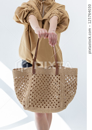 Female hand holding fashionable woven bag. Fashion and luxury accessories. Vertical photo. High quality photo Female hand holding fashionable woven bag. Fashion and luxury accessories. Vertical photo. High quality photo 125764030